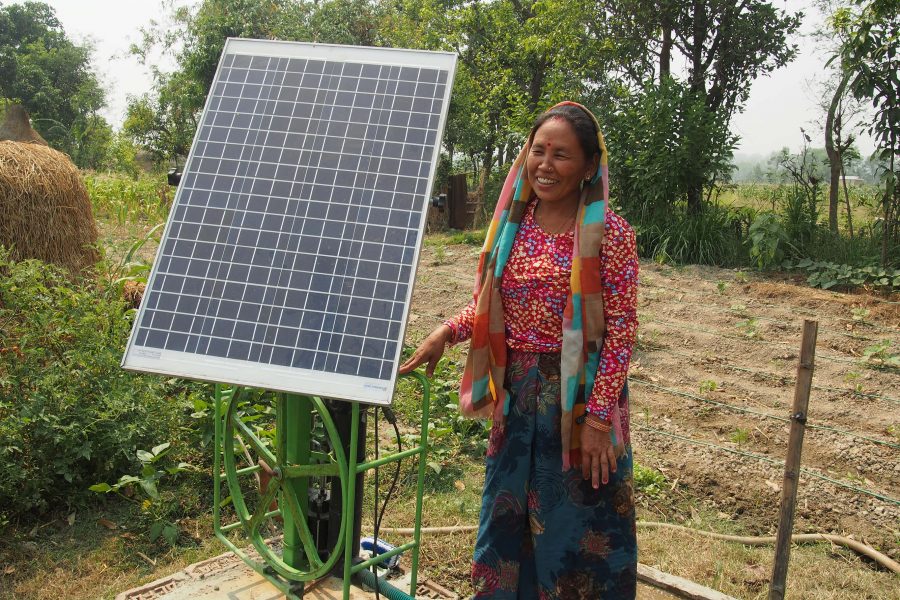 woman standing next to a solar panel in Nepal